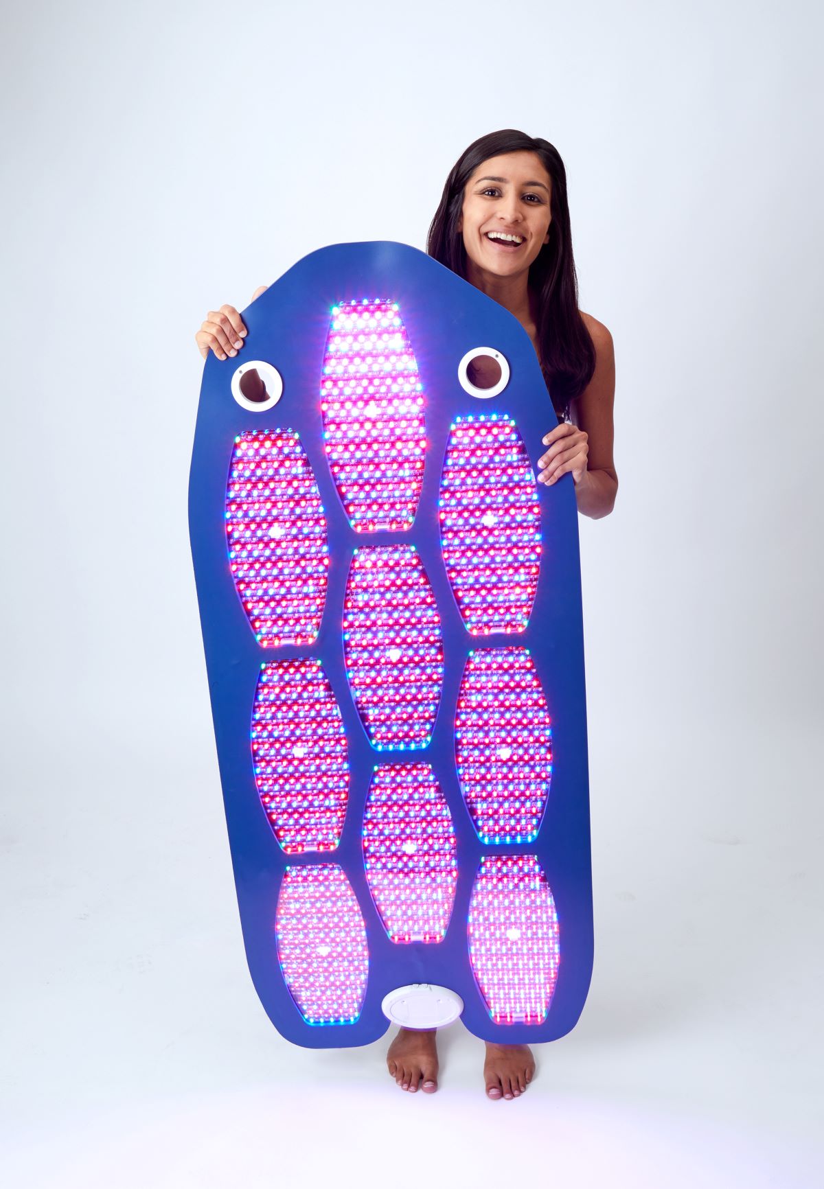Picture of the full body contour delux light therapy device with dark hair dark skin woman holding the device